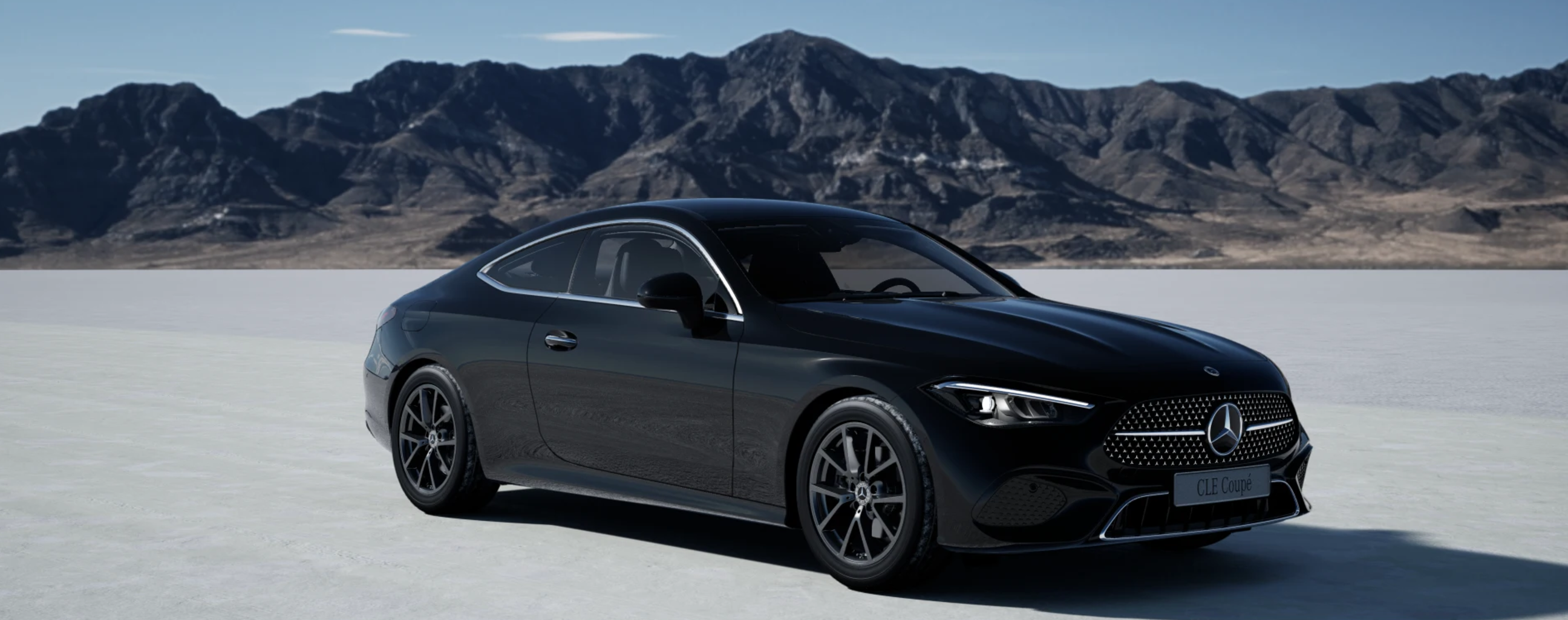 Ein schwarzes CLE Coupé in einer Salzwüste und im Hintergrund Berge.