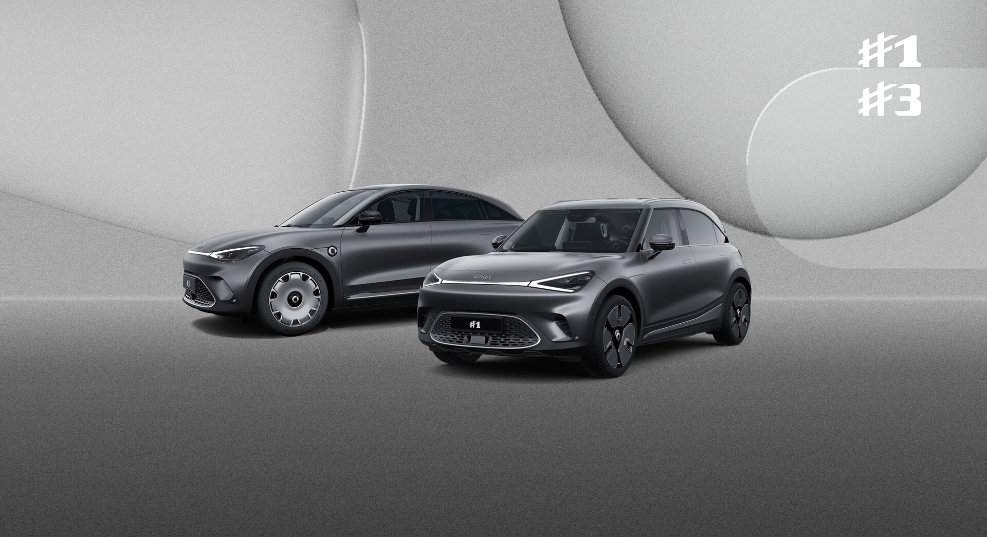 Die smart Modelle #1 und #3 stehen nebeneinander vor einem grauen Hintergrund. Die Fahrzeuge sind schwarz.